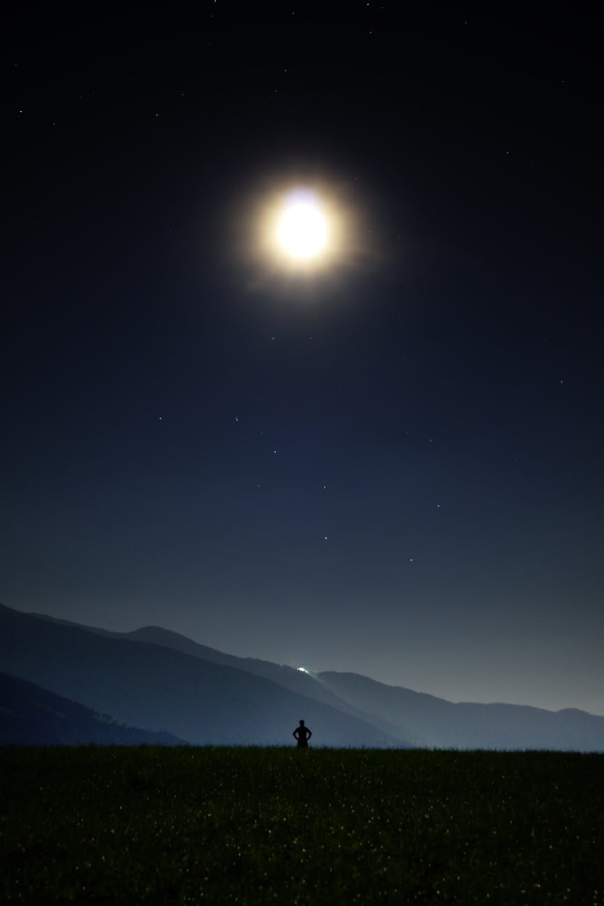 A person stands silhouetted against a moonlit night, stargazing in Brixen, Italy. A person stands silhouetted against a moonlit night, stargazing in Brixen, Italy.