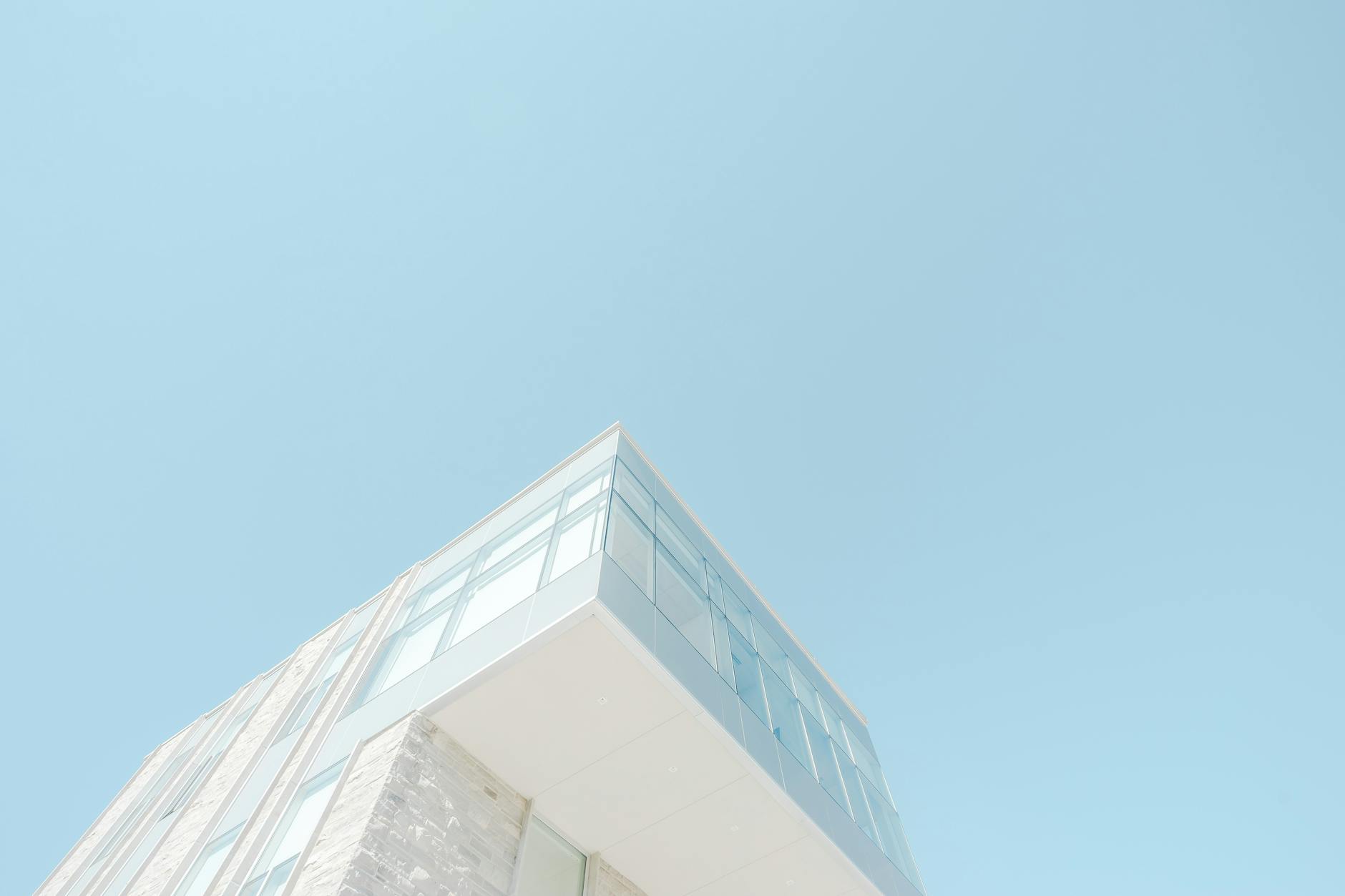 A low-angle shot of a modern building with a glass facade against a bright blue sky in London, Canada. A low-angle shot of a modern building with a glass facade against a bright blue sky in London, Canada.