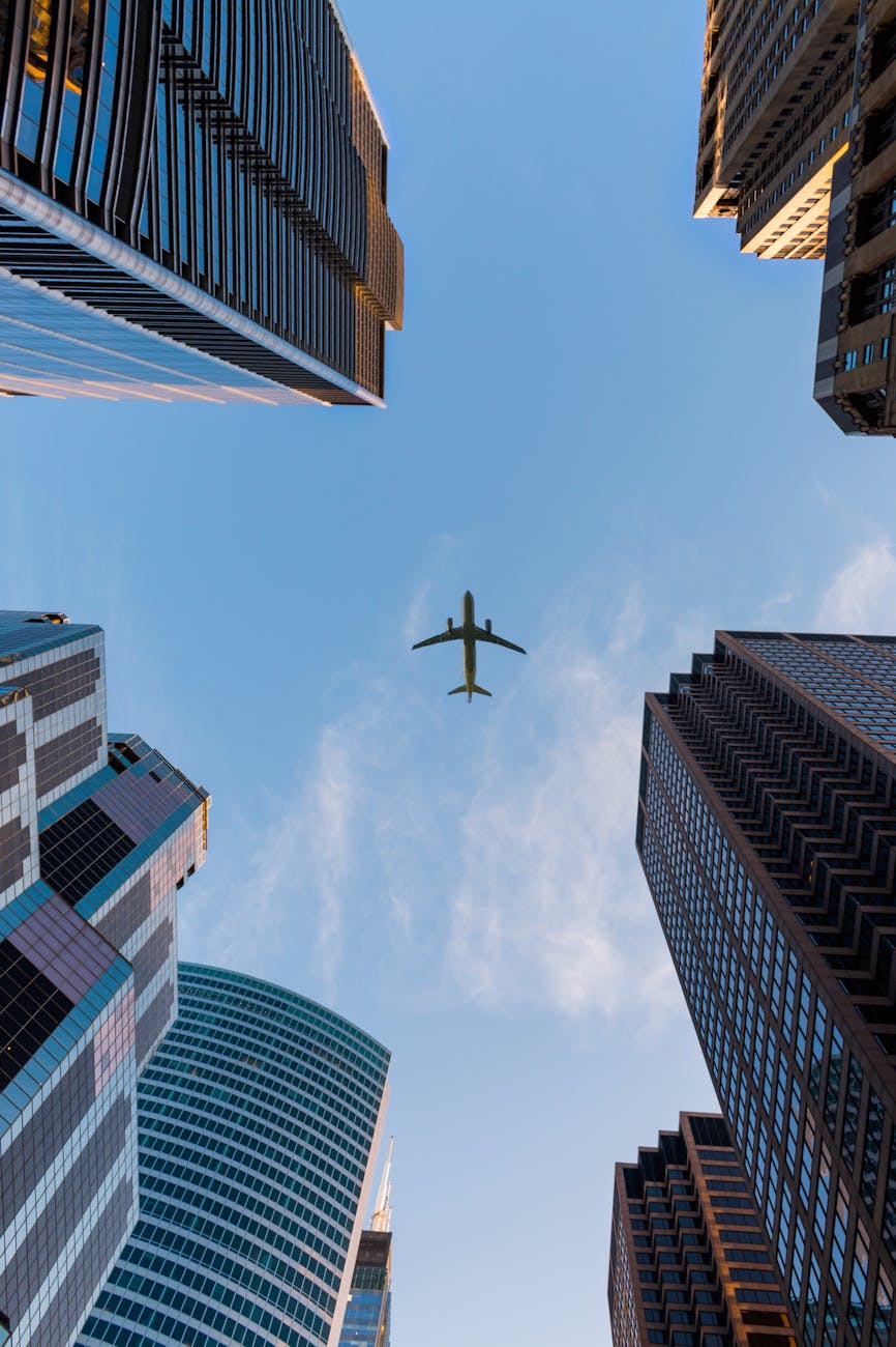 Airplane flies over Chicago’s modern skyscrapers against a clear sky, highlighting urban architecture.