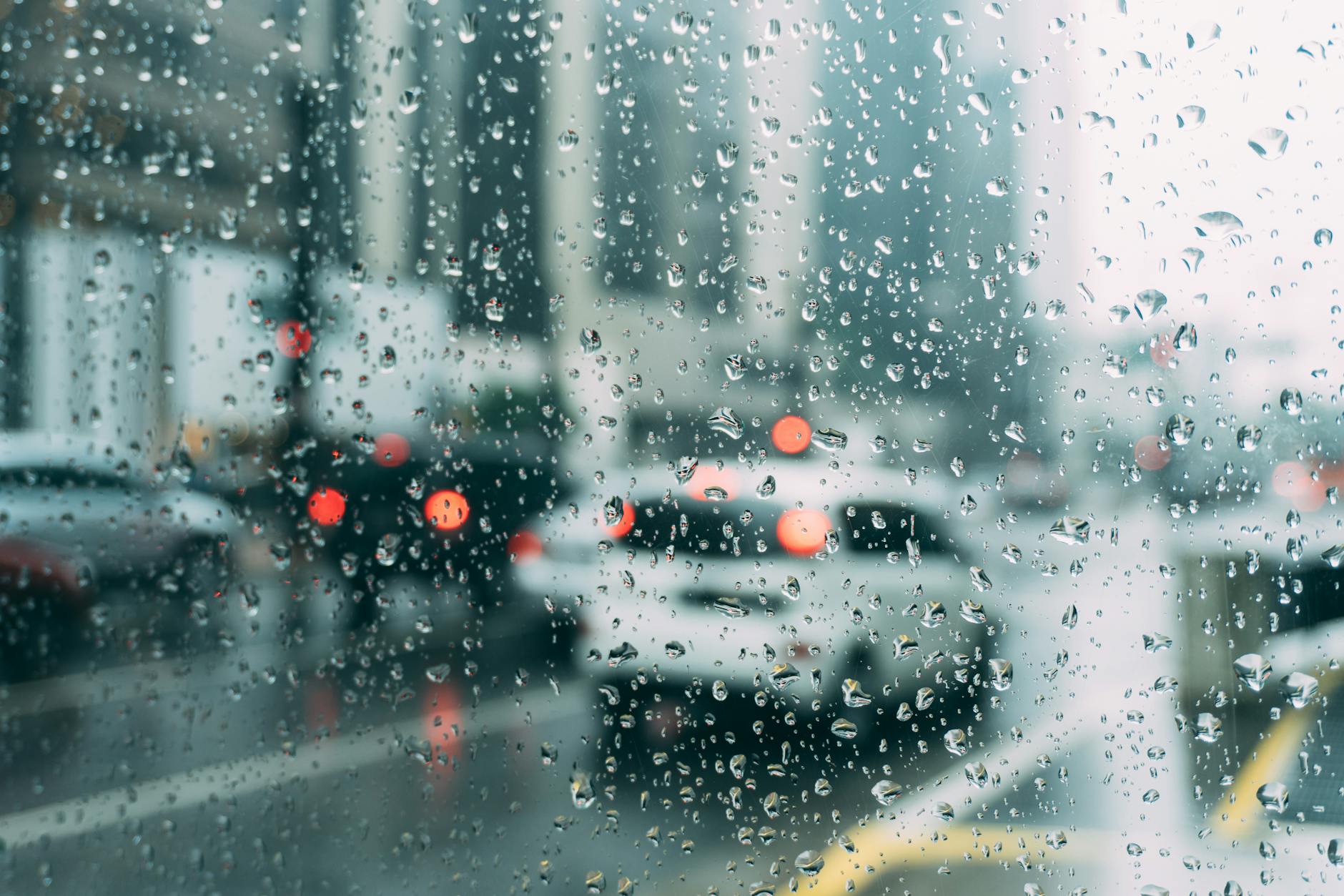 Blurred city traffic seen through a window with raindrops, a perfect rainy day scene.