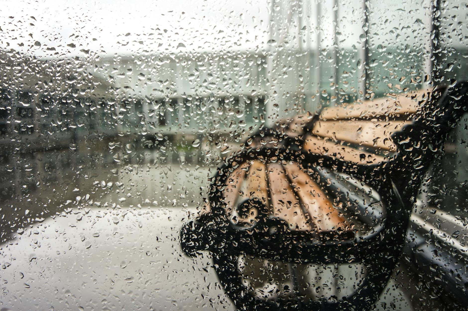 Rain-soaked window with a view of a bench outside in Fatih, Istanbul, Turkey.