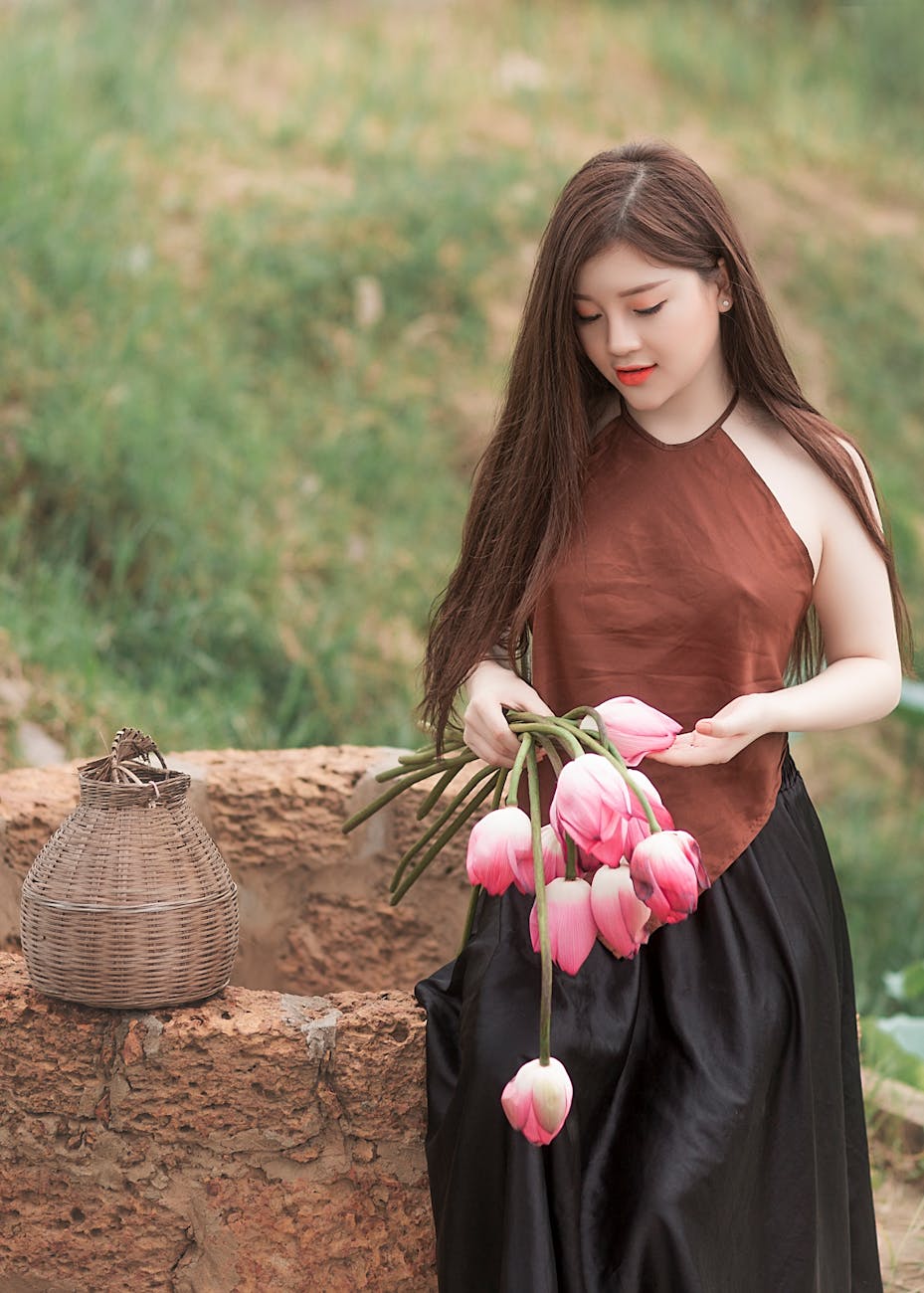 An elegant young woman holding pink tulips in a serene outdoor setting, embodying natural beauty and tranquility. An elegant young woman holding pink tulips in a serene outdoor setting, embodying natural beauty and tranquility.