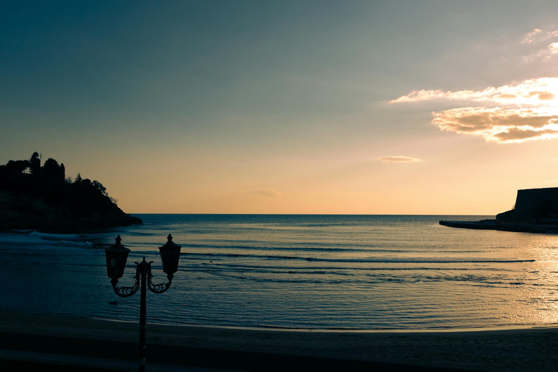 Serene beach at sunset in Ulcinj, Montenegro, with calm waves and vibrant skies.