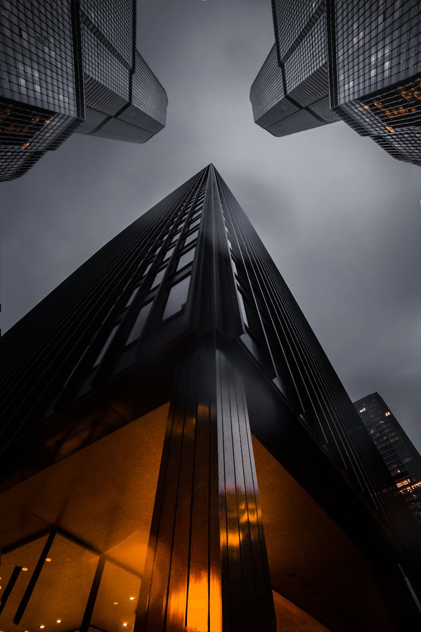 A low angle view of skyscrapers reaching into a moody night sky, showcasing modern architecture. A low angle view of skyscrapers reaching into a moody night sky, showcasing modern architecture.