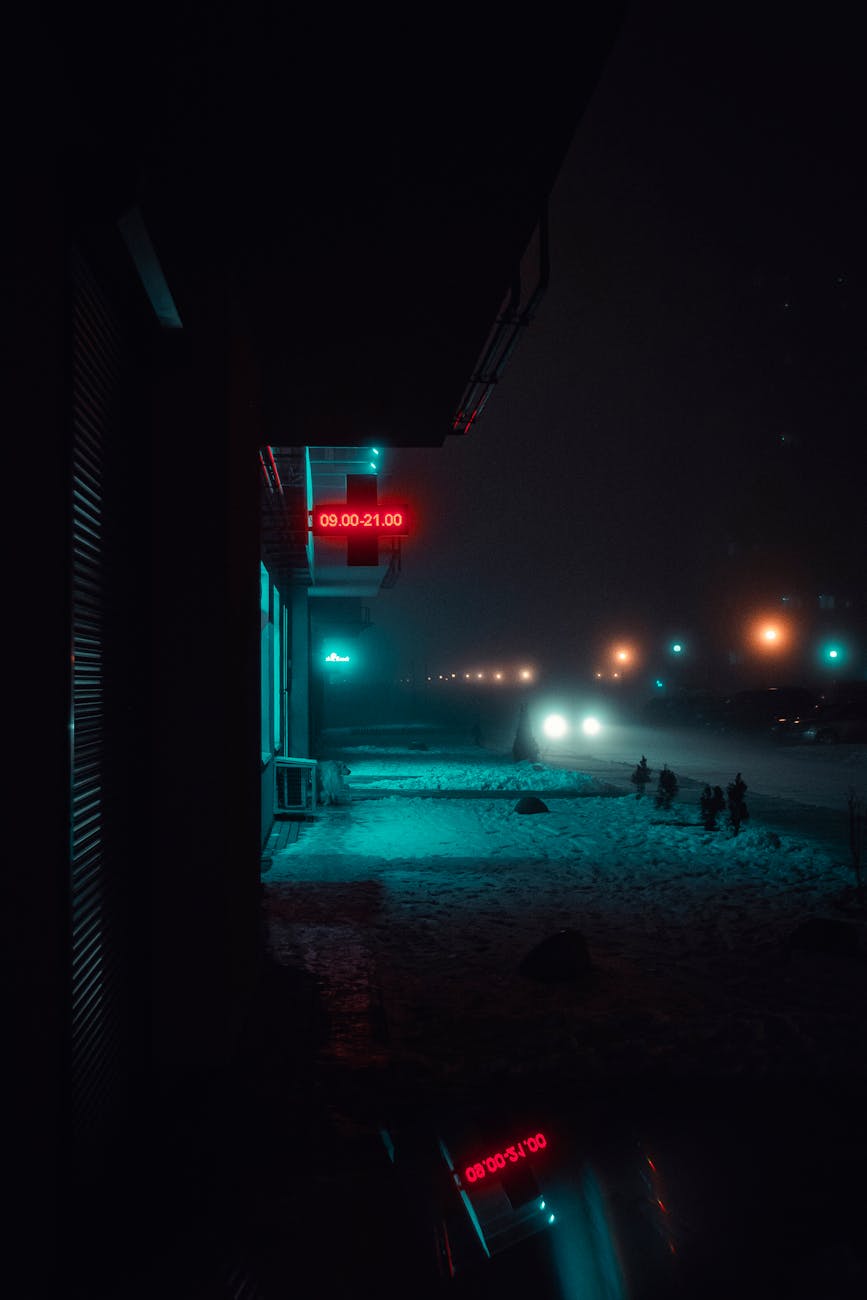Dramatic night street view with snow and neon signs, perfect for winter urban photography.
