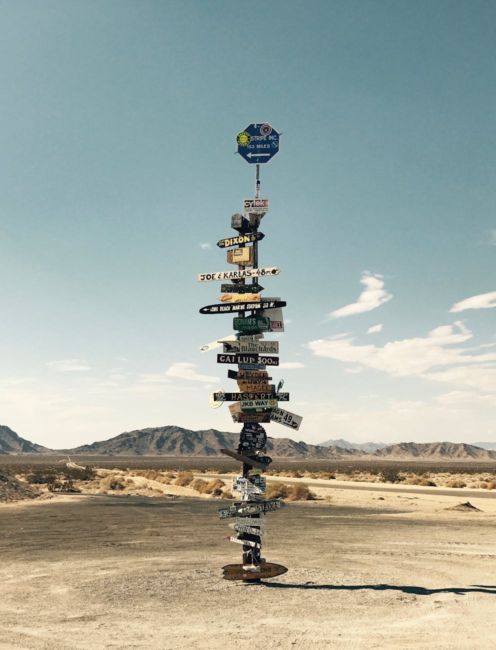 Tall signpost in a desert landscape under a clear blue sky with mountains in the background. Tall signpost in a desert landscape under a clear blue sky with mountains in the background.