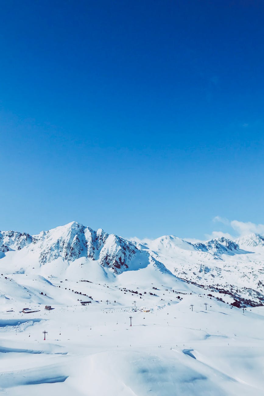 Majestic snowy mountains in Andorra under a vibrant blue sky, perfect for winter sports.
