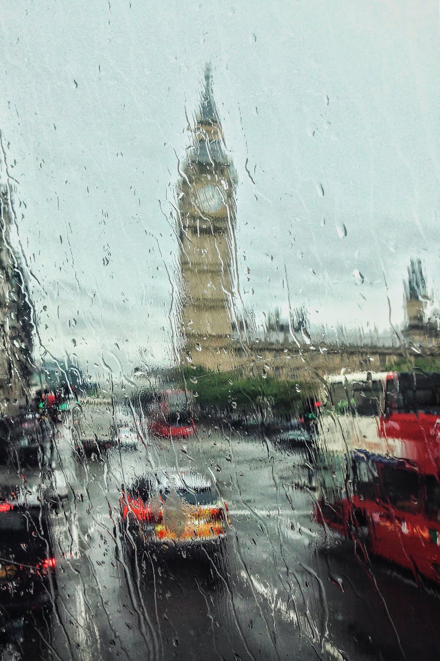 Moody view of Big Ben through a rain-soaked window, capturing London’s iconic weather and city life.