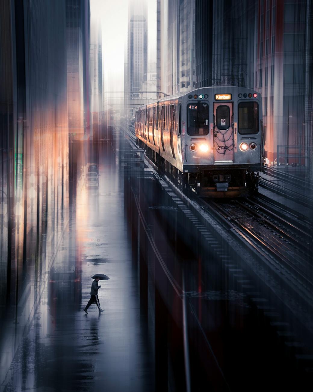 Dramatic cityscape with a fast-moving train and a commuter crossing in the rain at dusk. Dramatic cityscape with a fast-moving train and a commuter crossing in the rain at dusk.