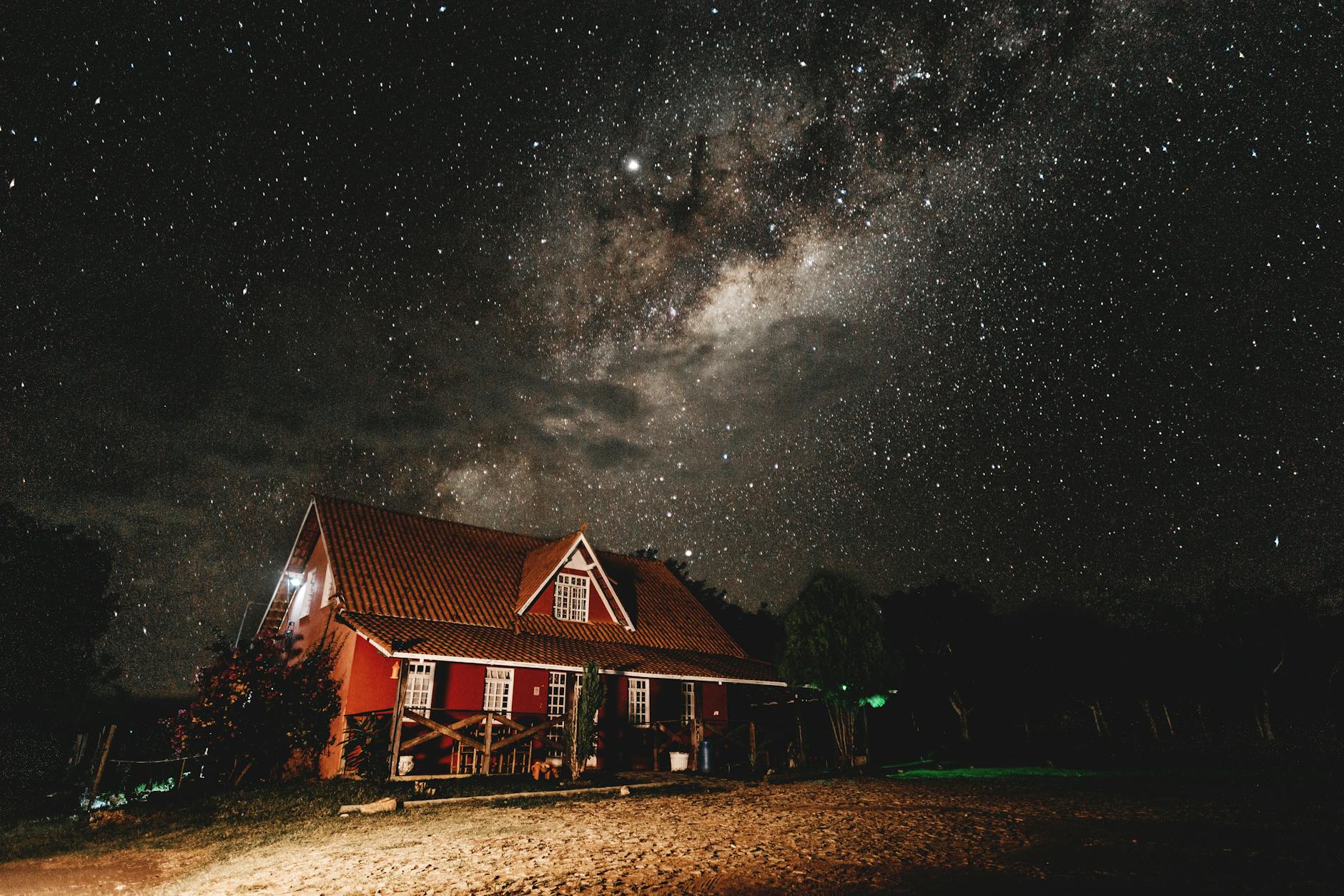 A beautiful starry night sky with the Milky Way over a rustic house, perfect for astronomy lovers.