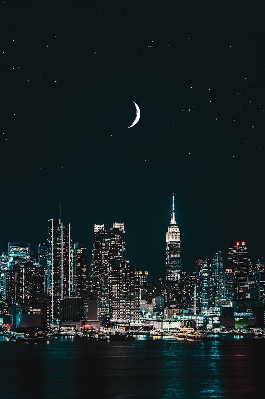 Stunning night view of New York City skyline with a crescent moon and stars illuminating the scene.