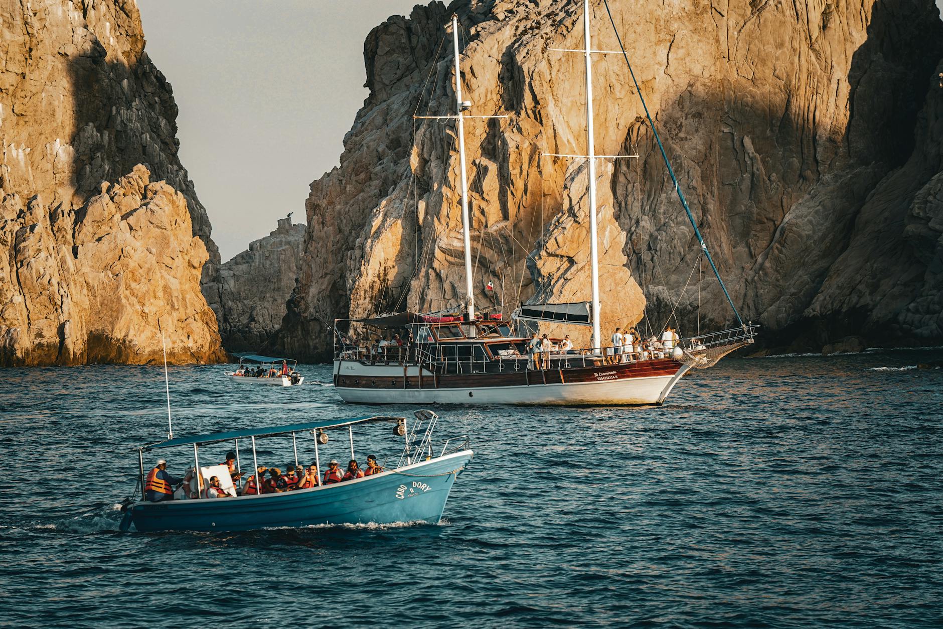Boats navigate through stunning rocky coastal cliffs during daytime adventure tour.