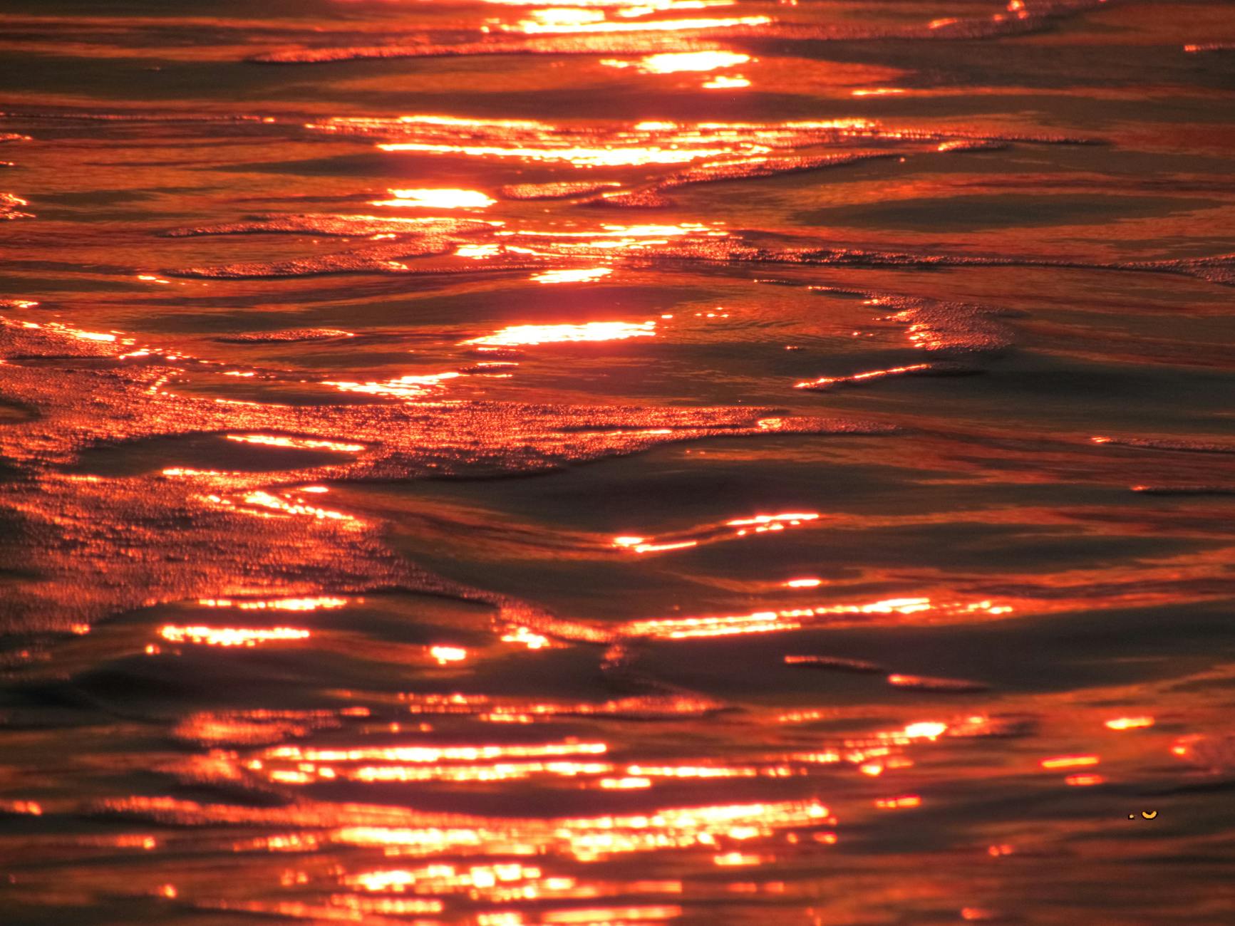 Captivating reflection of a vibrant sunset on ocean waves, creating a dramatic and warm ambiance.