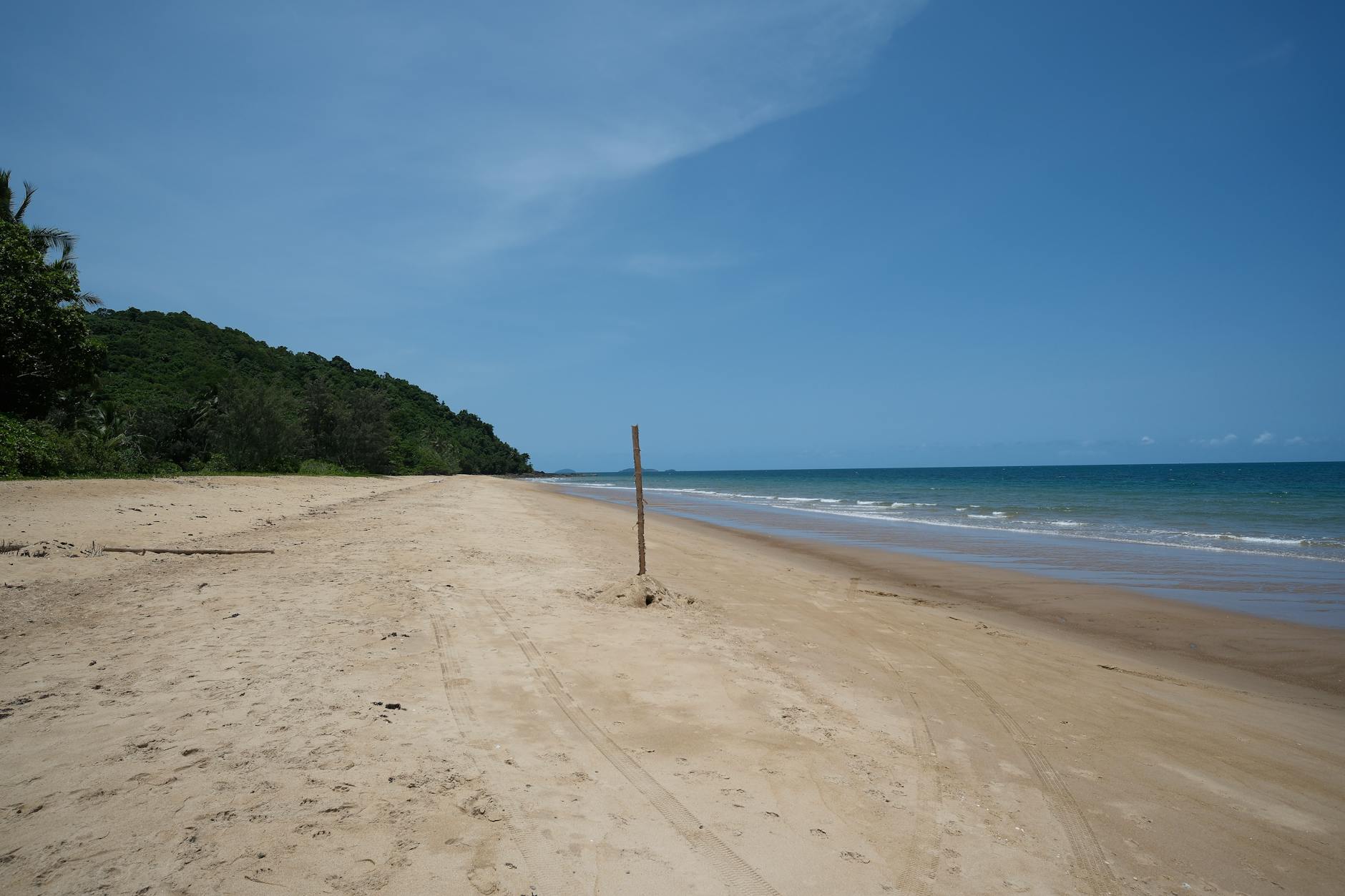 A tranquil tropical beach with golden sand and clear blue sky, perfect for relaxation and travel.