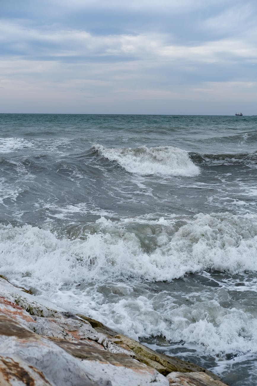 A striking view of powerful waves crashing on Büyükçekmece’s rocky shore under a cloudy sky.