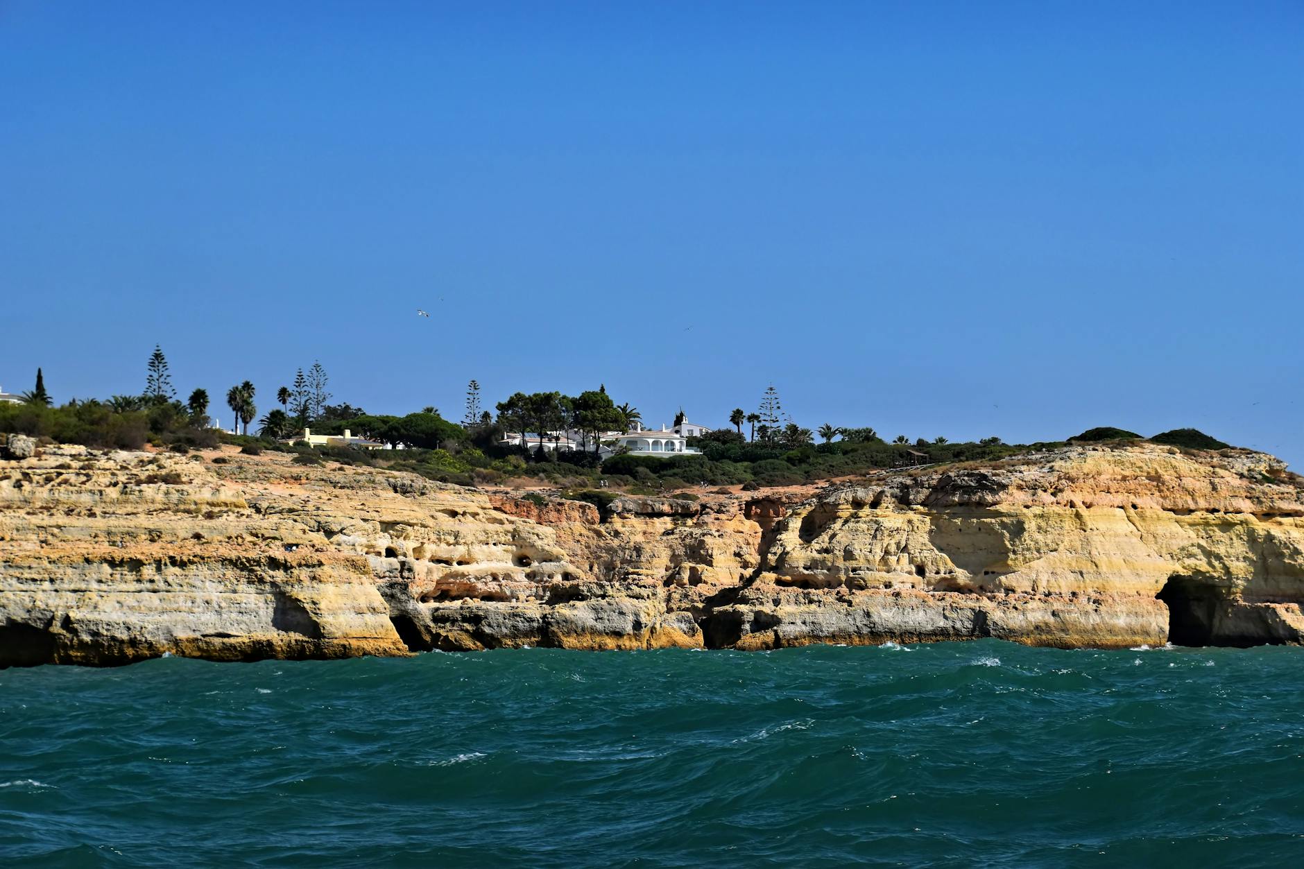 Beautiful coastal cliffs with clear blue water in Faro District, Portugal, captured under a sunny sky. Beautiful coastal cliffs with clear blue water in Faro District, Portugal, captured under a sunny sky.