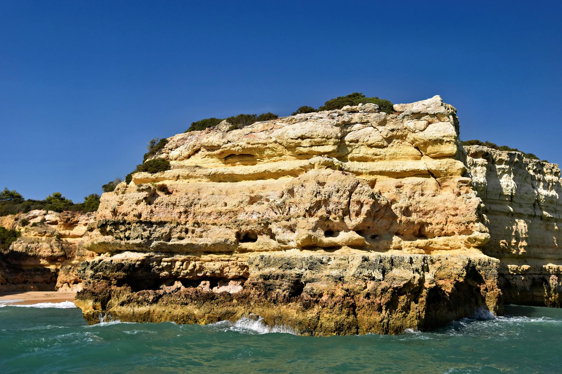Dramatic coastal cliff formations in Algarve, Portugal, under clear blue skies. Dramatic coastal cliff formations in Algarve, Portugal, under clear blue skies.