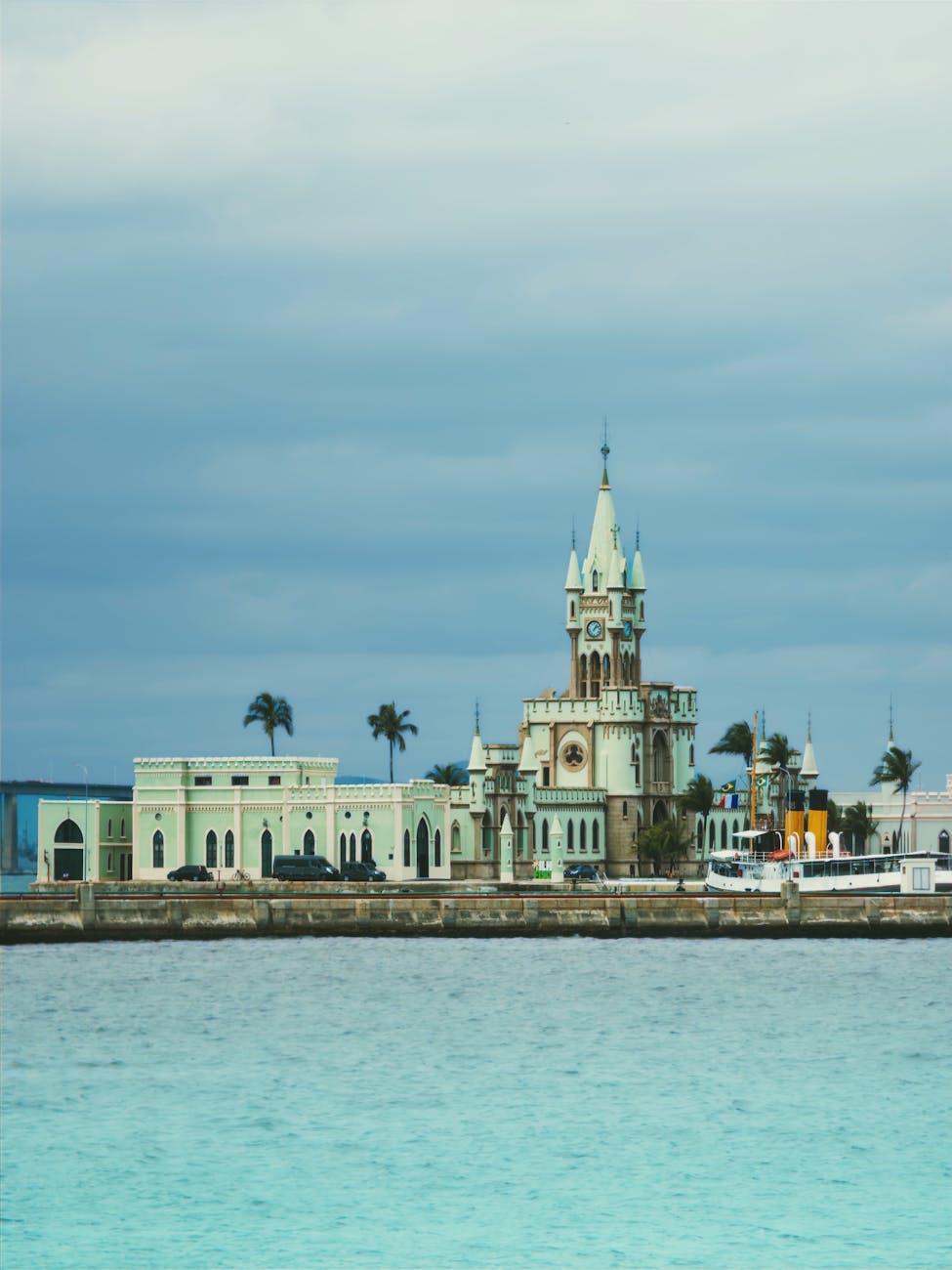 A historic clock tower standing by the waterfront under a cloudy sky, exuding a vintage charm. A historic clock tower standing by the waterfront under a cloudy sky, exuding a vintage charm.