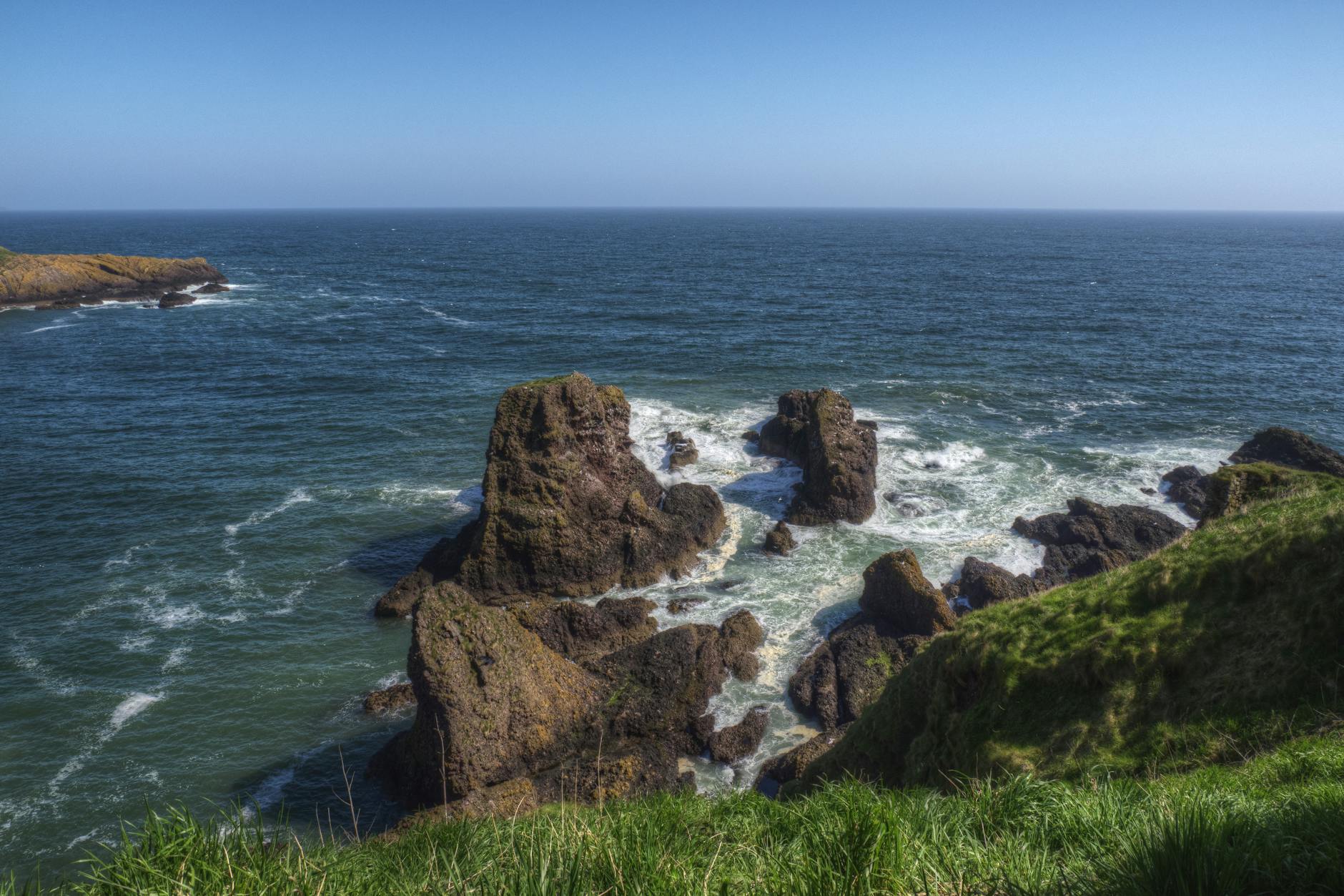 Stunning view of rocky coastal cliffs with vibrant blue ocean under clear sky. Stunning view of rocky coastal cliffs with vibrant blue ocean under clear sky.