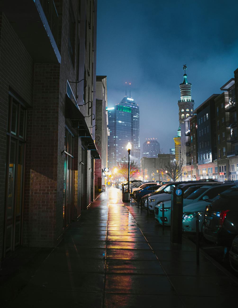 A captivating view of the Indianapolis skyline with parked cars and illuminated streets at night. A captivating view of the Indianapolis skyline with parked cars and illuminated streets at night.