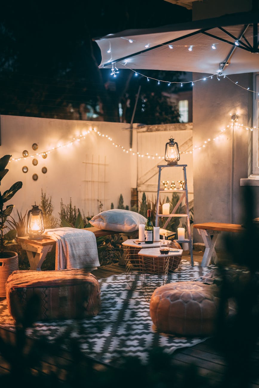 Warmly lit outdoor patio with cozy seating, lanterns, and decorative lights. Warmly lit outdoor patio with cozy seating, lanterns, and decorative lights.