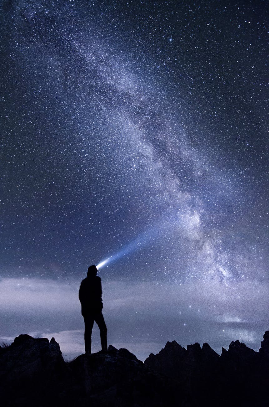 Silhouette of a person exploring the star-studded Milky Way sky at night in the mountains.