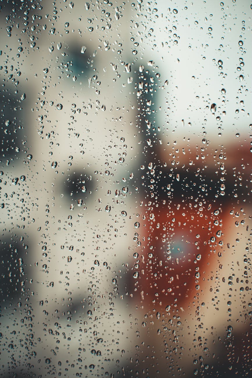 Closeup of water drops on transparent misted glass during rain as abstract background