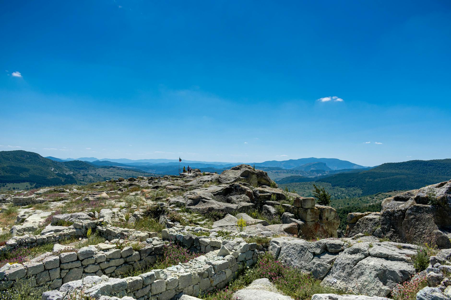 Explore ancient ruins set against a breathtaking mountain backdrop under a clear blue sky. Explore ancient ruins set against a breathtaking mountain backdrop under a clear blue sky.