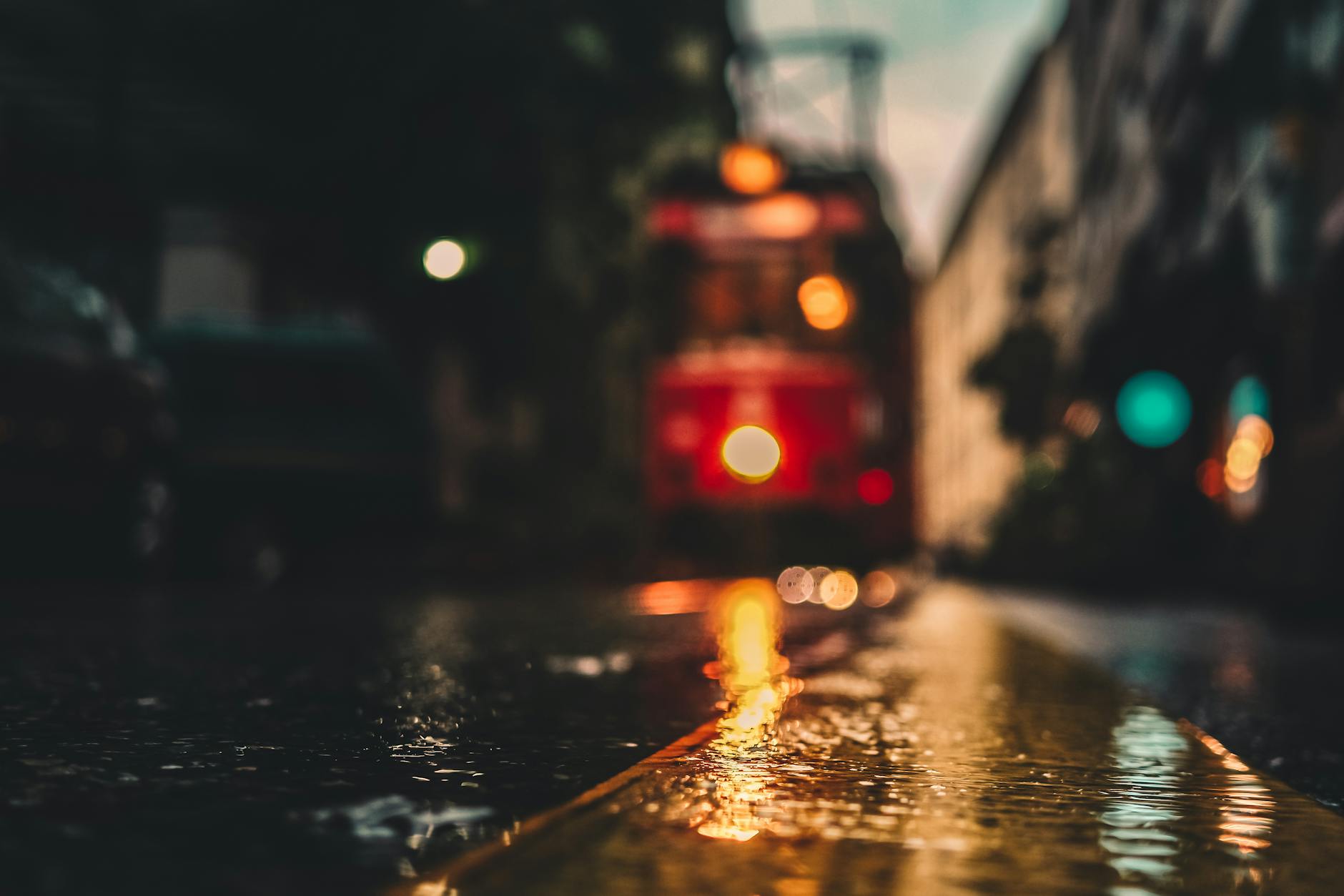 A moody, blurry shot of an urban street reflecting lights with a tram in the background.