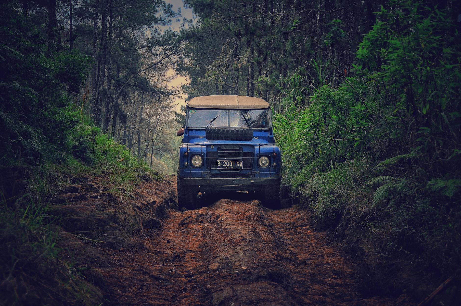 Off-road vehicle traversing a rugged dirt path through lush forest in Parongpong, Indonesia. Off-road vehicle traversing a rugged dirt path through lush forest in Parongpong, Indonesia.