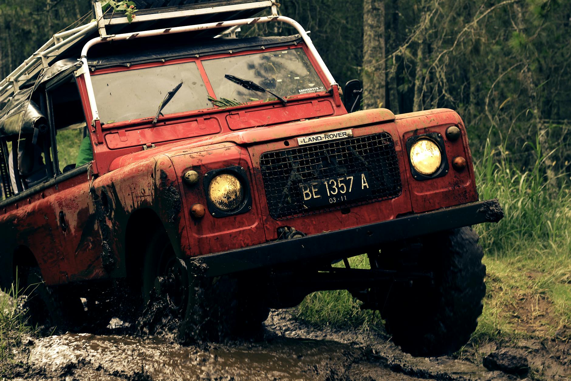 A rugged vintage Land Rover conquers a muddy trail, showcasing off-road capabilities and adventure spirit.
