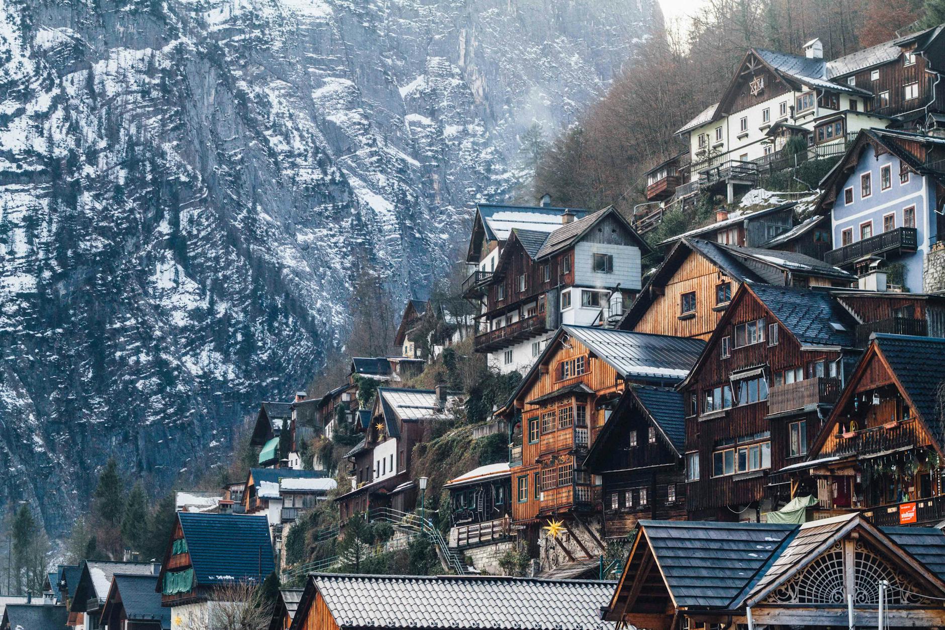 Charming wooden homes nestled on a snowy cliffside in Liezen, Austria, during winter.