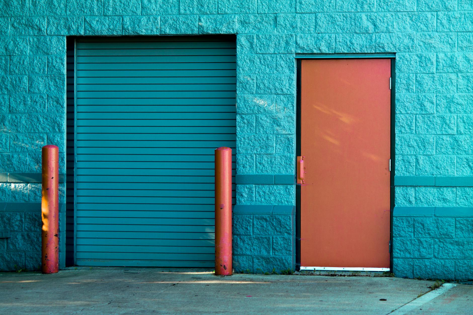 Vivid blue wall with a closed door and shutter in Valparaiso’s urban setting.