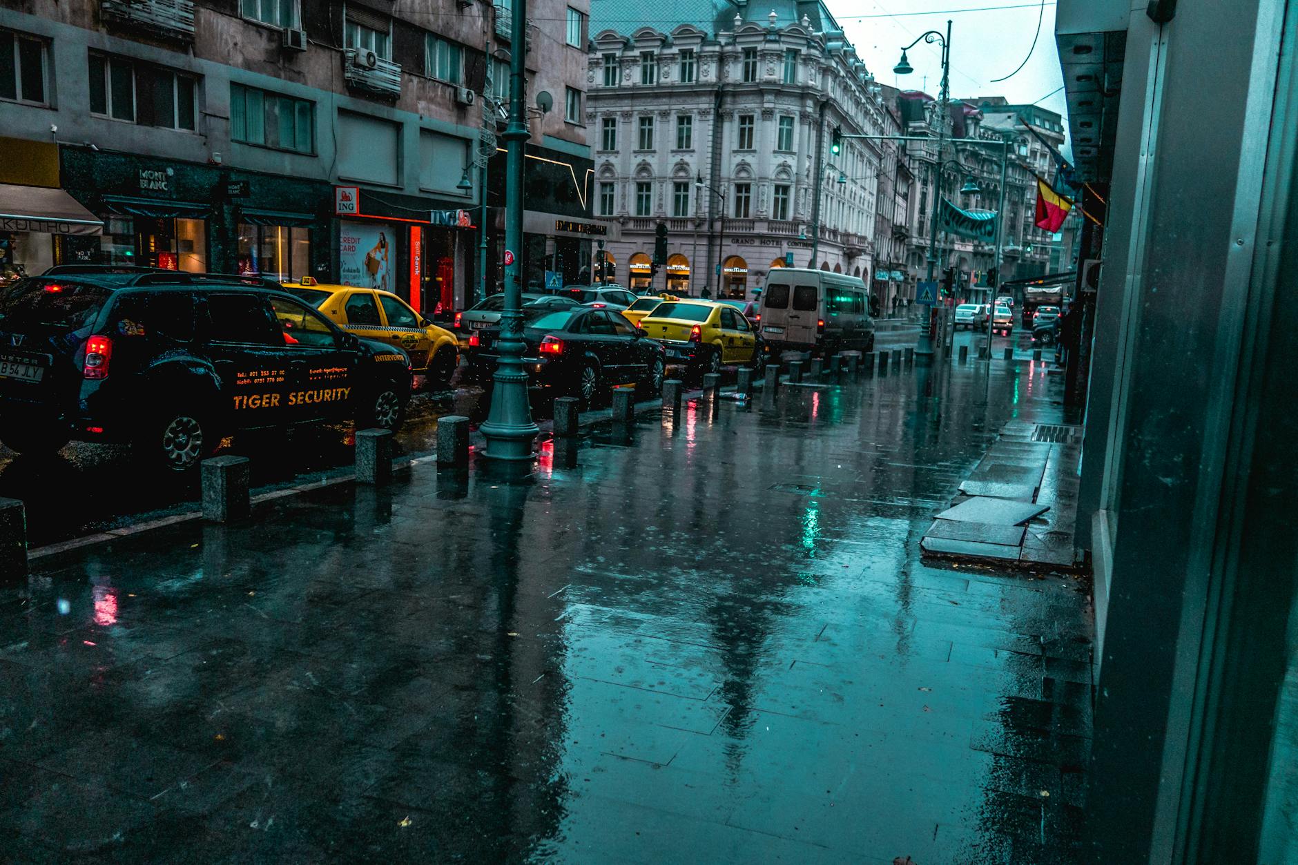 A wet city street with traffic and classic architecture, reflecting calm ambiance on a rainy day. A wet city street with traffic and classic architecture, reflecting calm ambiance on a rainy day.