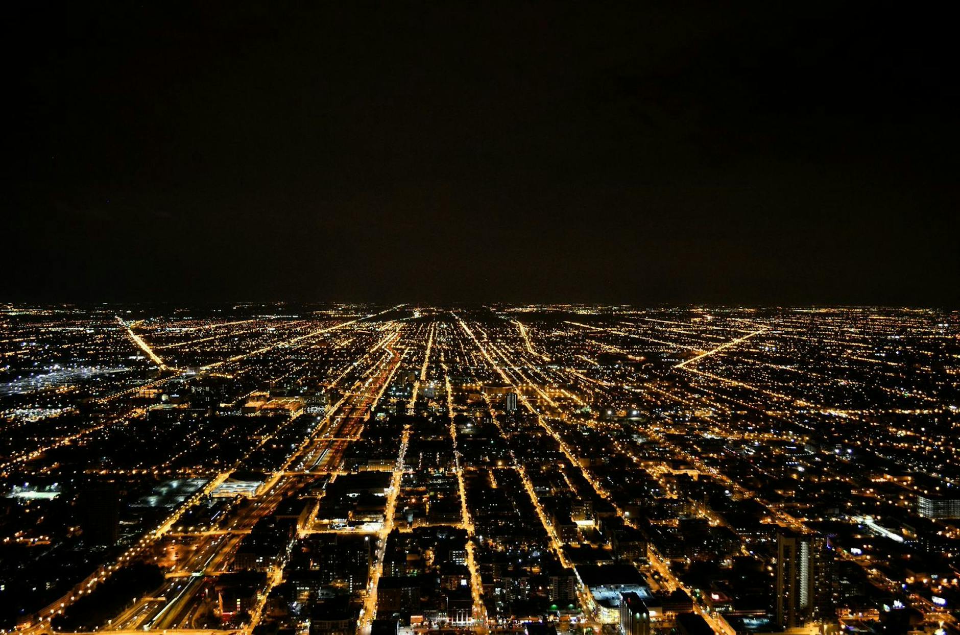 A breathtaking aerial view of a sprawling city illuminated by glowing lights against the night sky.