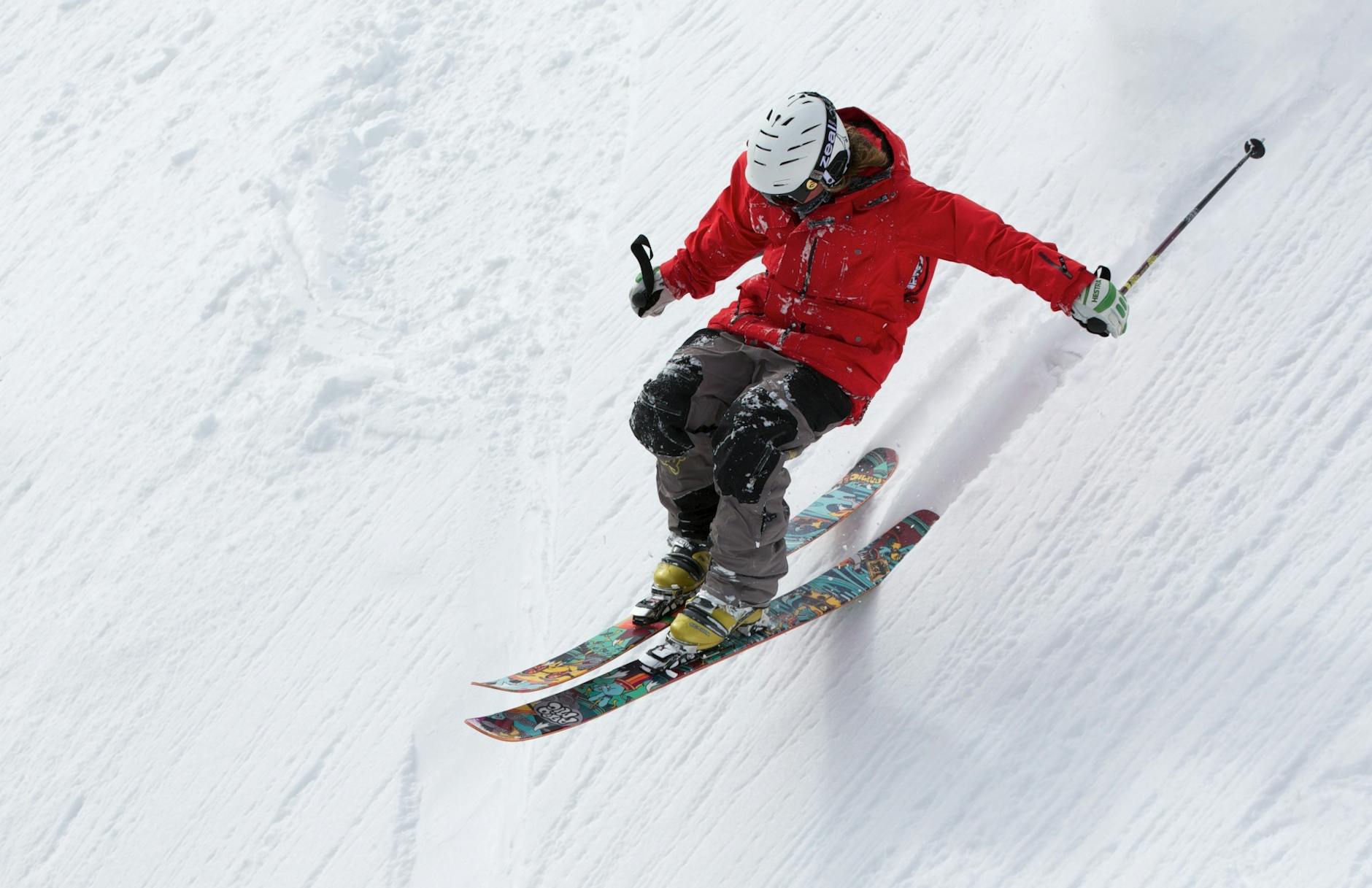A skier in a red jacket descends a steep snowy slope, showcasing skill and adventure in winter sports. A skier in a red jacket descends a steep snowy slope, showcasing skill and adventure in winter sports.