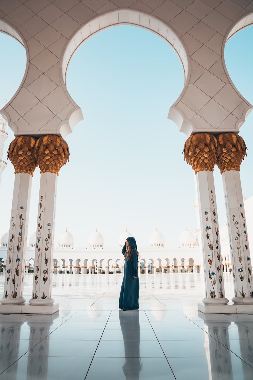 A person in traditional attire standing among columns of the Sheikh Zayed Mosque in Abu Dhabi. A person in traditional attire standing among columns of the Sheikh Zayed Mosque in Abu Dhabi.