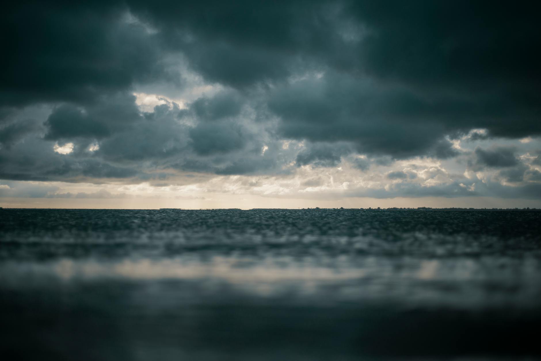 A captivating view of the ocean with dramatic dark clouds above, presenting a moody and dramatic seascape. A captivating view of the ocean with dramatic dark clouds above, presenting a moody and dramatic seascape.