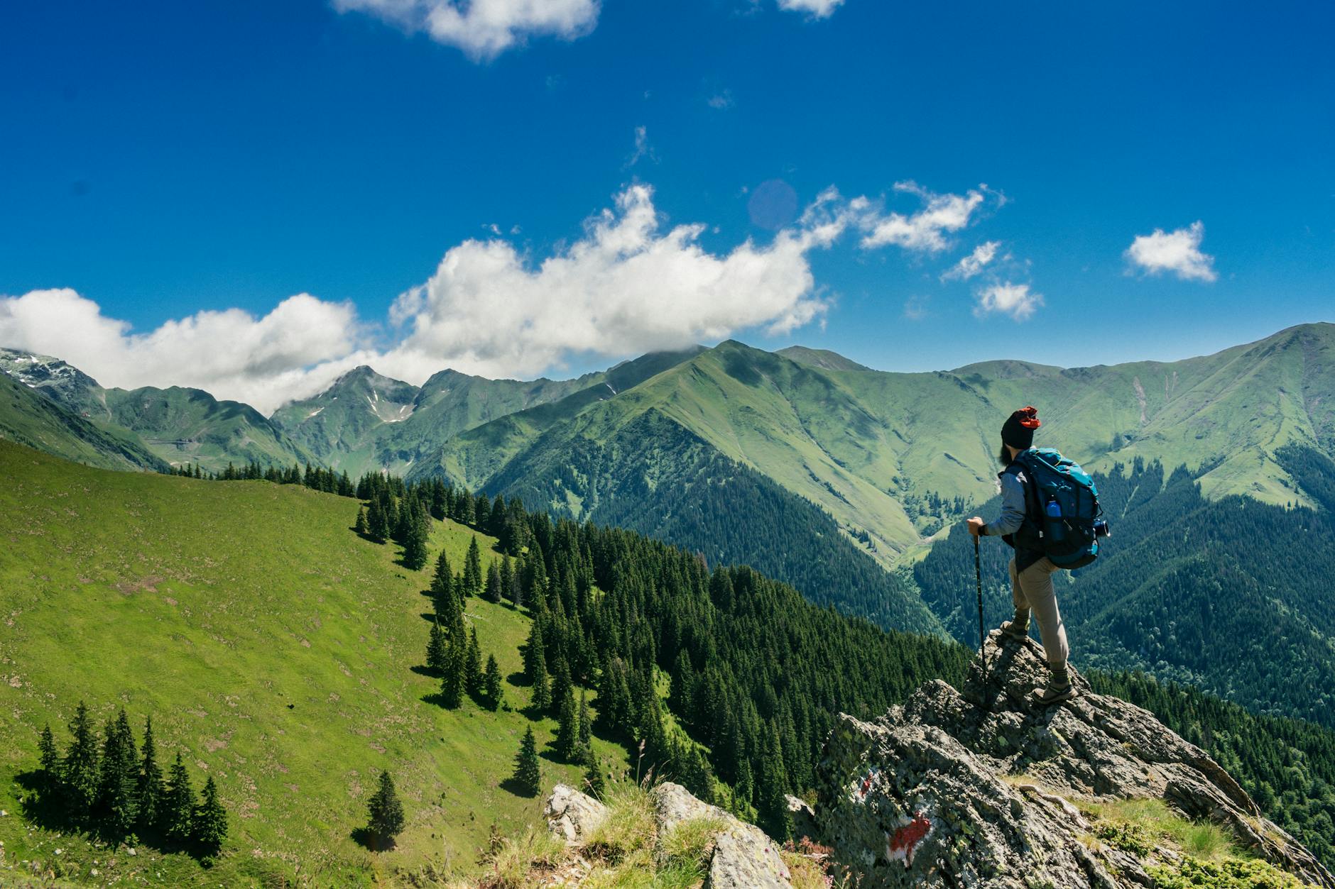 Adventurous hiker enjoying breathtaking views of lush green mountains in Romania under a clear blue sky. Adventurous hiker enjoying breathtaking views of lush green mountains in Romania under a clear blue sky.