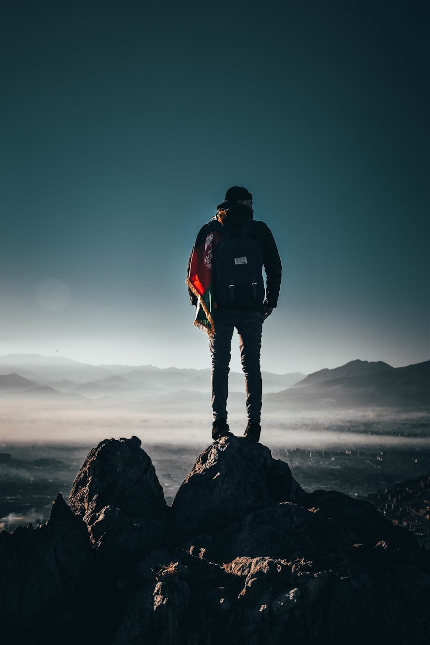 A lone hiker stands on a rocky peak, overlooking breathtaking mountains at sunrise in Afghanistan. A lone hiker stands on a rocky peak, overlooking breathtaking mountains at sunrise in Afghanistan.