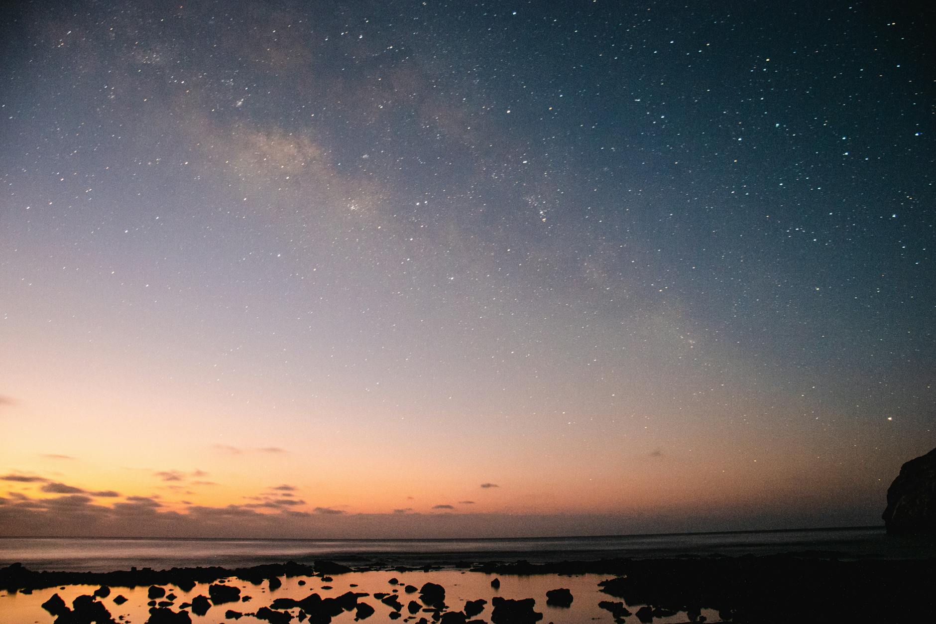 Serene seascape at dusk with stars illuminating the night sky over a calm ocean view.