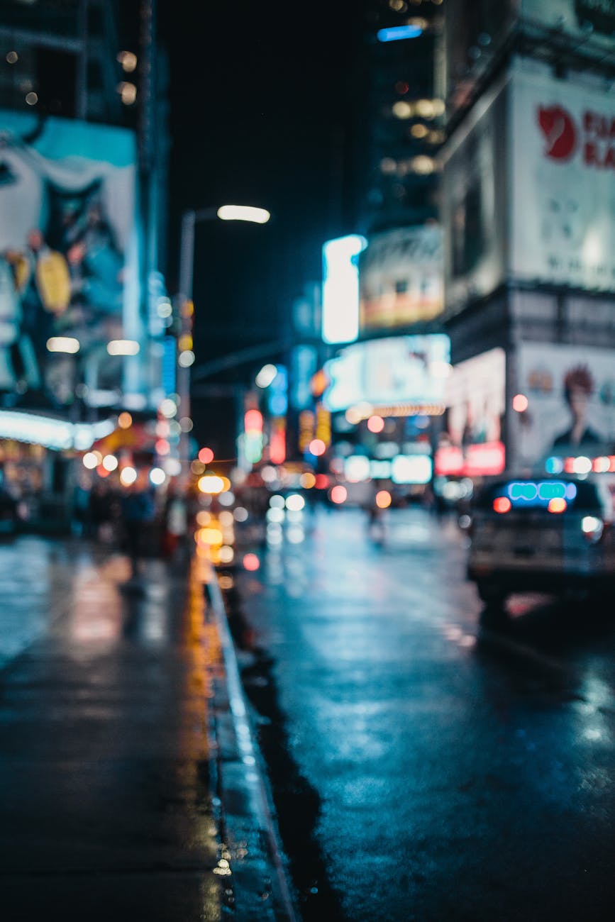 Moody, out-of-focus urban nightscape with neon city lights and wet streets.