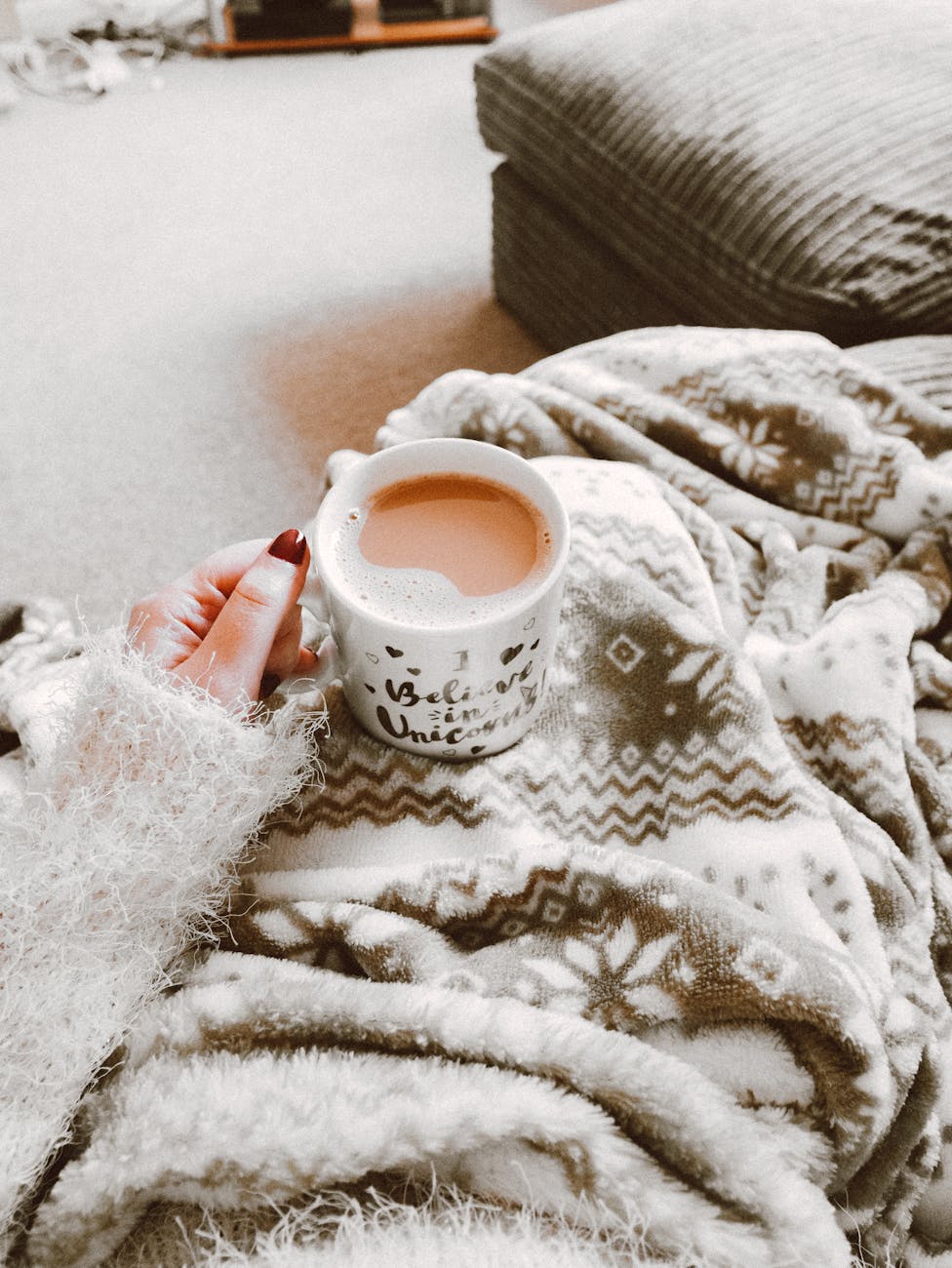 Person holding a hot drink surrounded by cozy blanket indoors. Perfect for winter comfort. Person holding a hot drink surrounded by cozy blanket indoors. Perfect for winter comfort.
