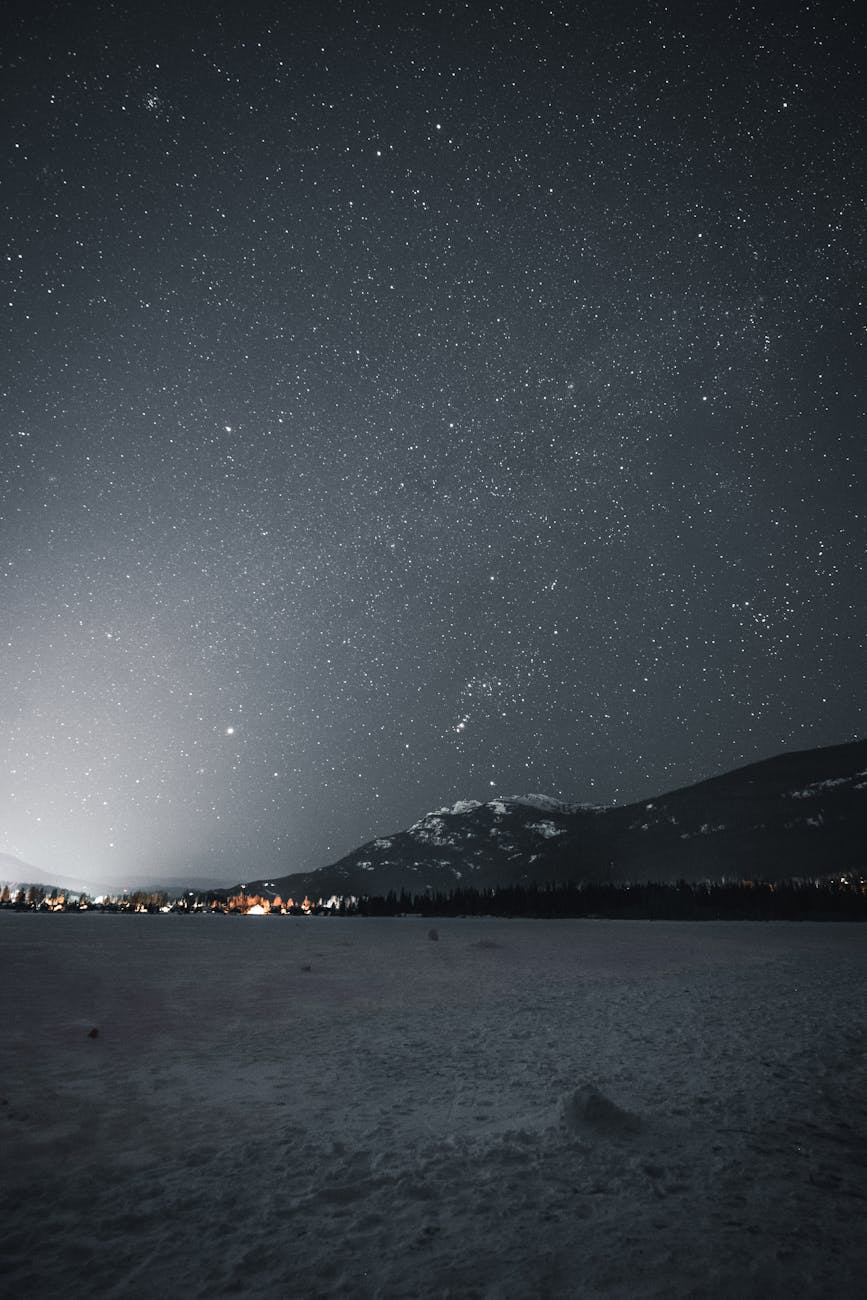 A breathtaking view of a starry night sky over a snowy mountain landscape during winter. A breathtaking view of a starry night sky over a snowy mountain landscape during winter.