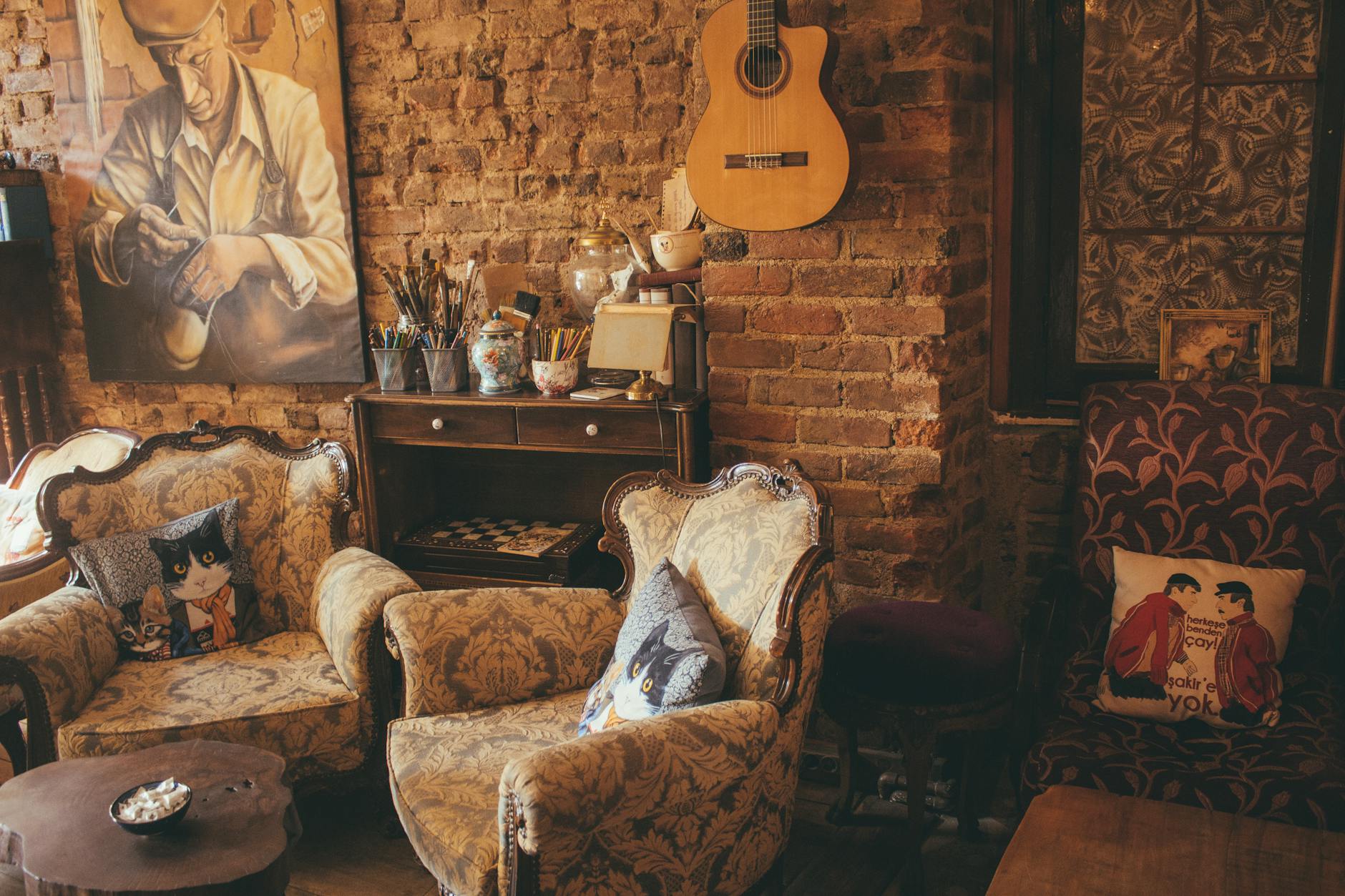 Warm vintage room with armchairs, guitar, and artwork on a brick wall, creating a cozy atmosphere. Warm vintage room with armchairs, guitar, and artwork on a brick wall, creating a cozy atmosphere.