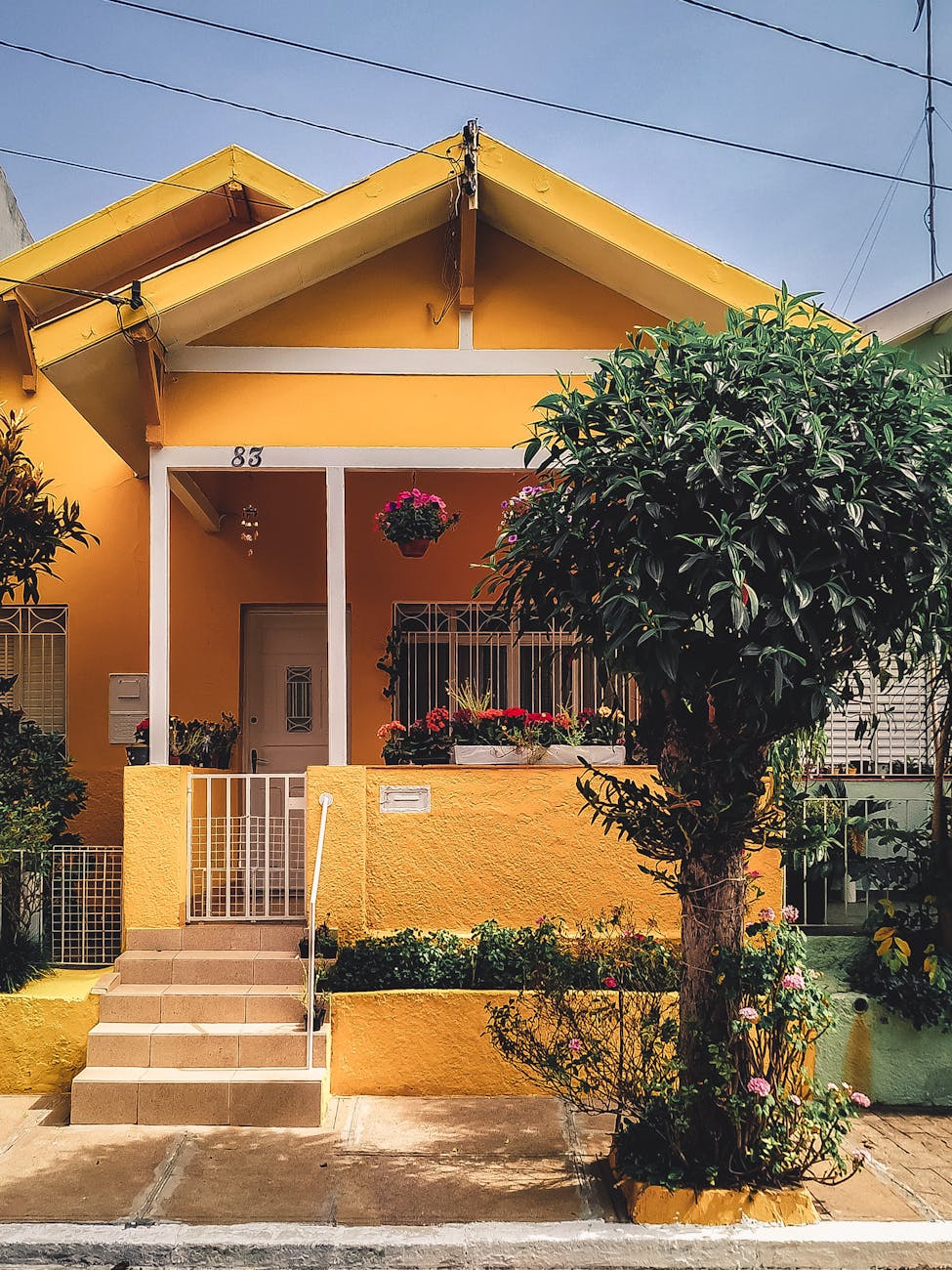 Bright yellow house with lush garden, vibrant flowers, and welcoming porch entrance. Bright yellow house with lush garden, vibrant flowers, and welcoming porch entrance.