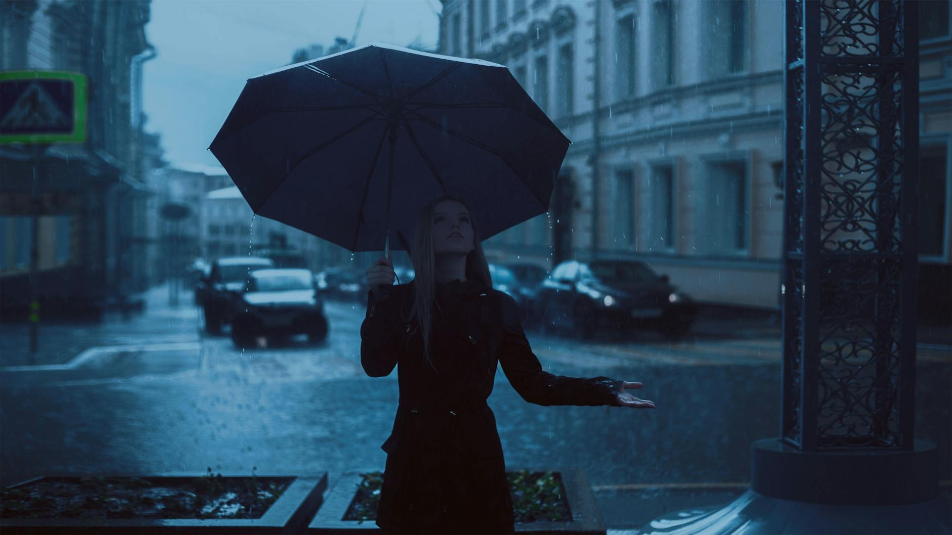Woman under an umbrella during a rainy day in a moody cityscape scene.