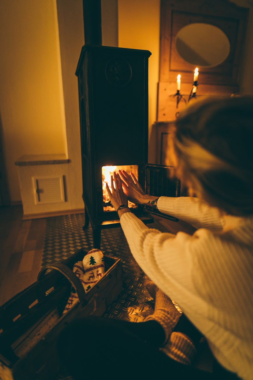 A woman enjoying warmth by a fireplace in a cozy room. Perfect for winter relaxation themes.