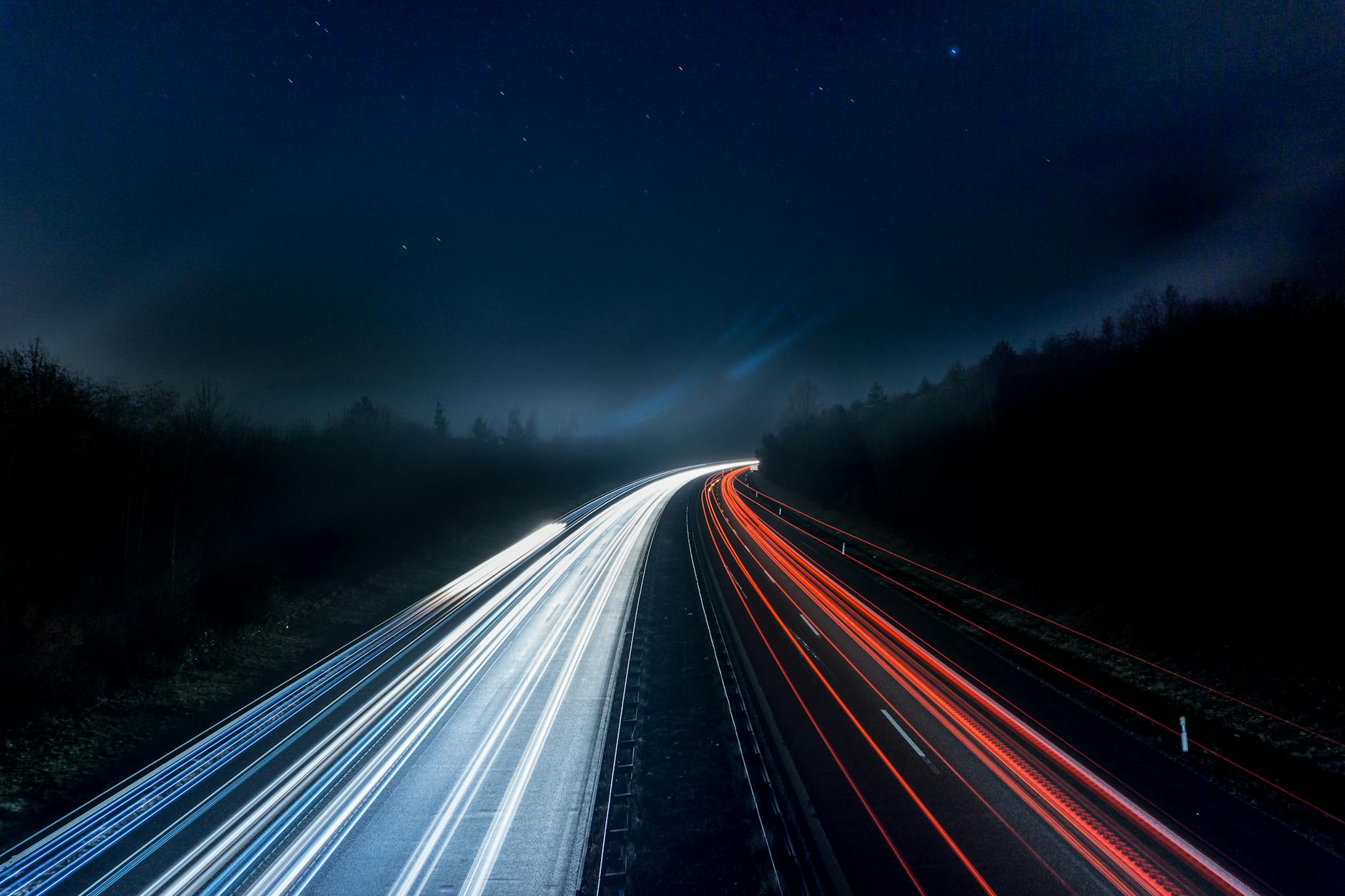Long exposure night shot capturing stunning red and white light trails on a highway under a starry sky. Long exposure night shot capturing stunning red and white light trails on a highway under a starry sky.