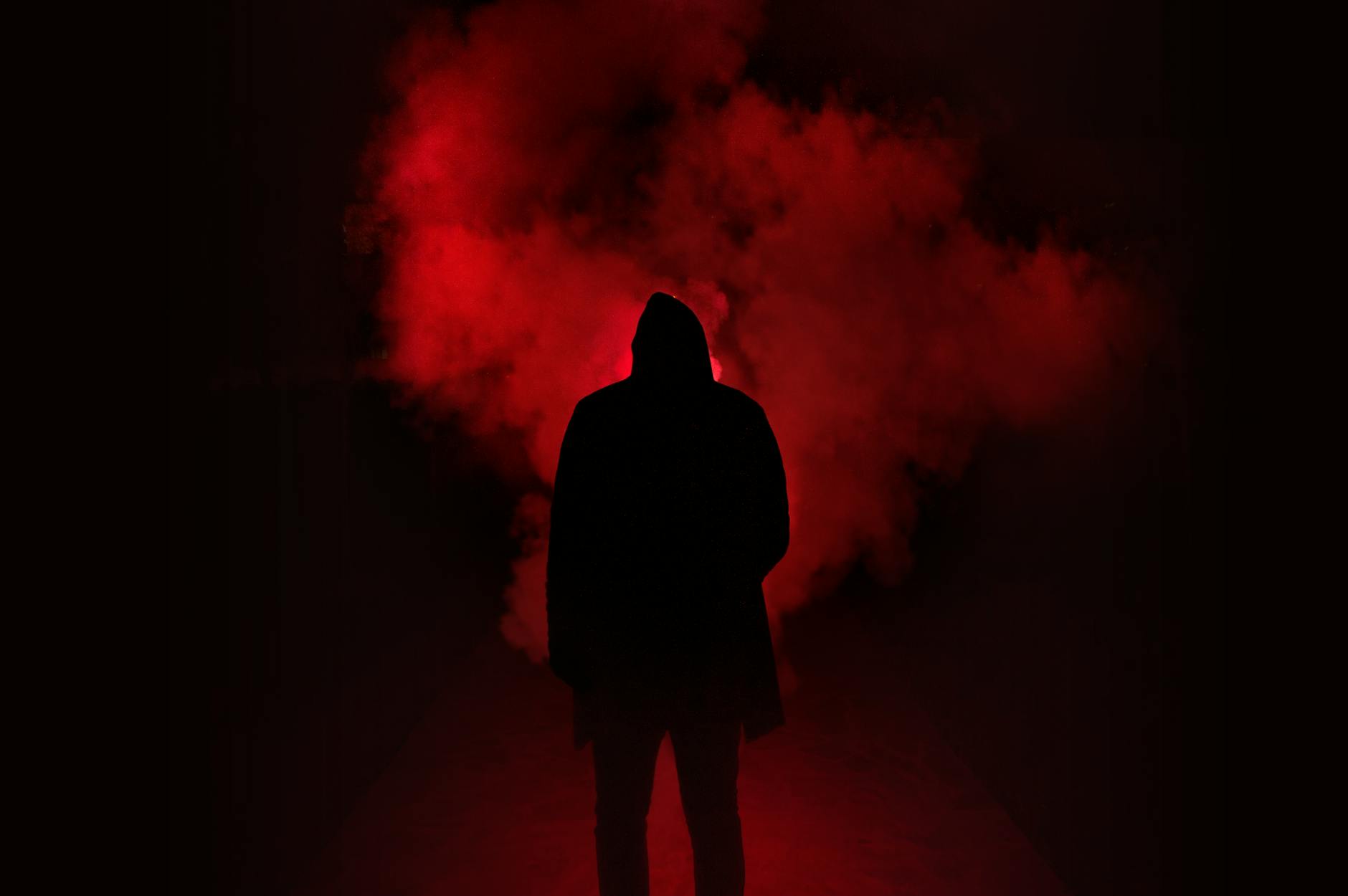A mysterious silhouette standing against a backdrop of dramatic red smoke. A mysterious silhouette standing against a backdrop of dramatic red smoke.